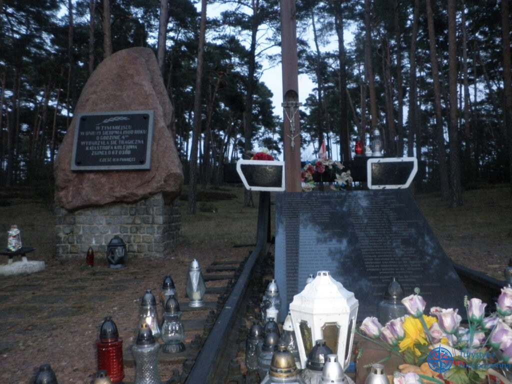 na lewo kamień z tablicą z napisem "w tym miejscu dnia 19 sierpnia 1980 roku..." po prawo pomnik Katastrofa w Otłoczynie
