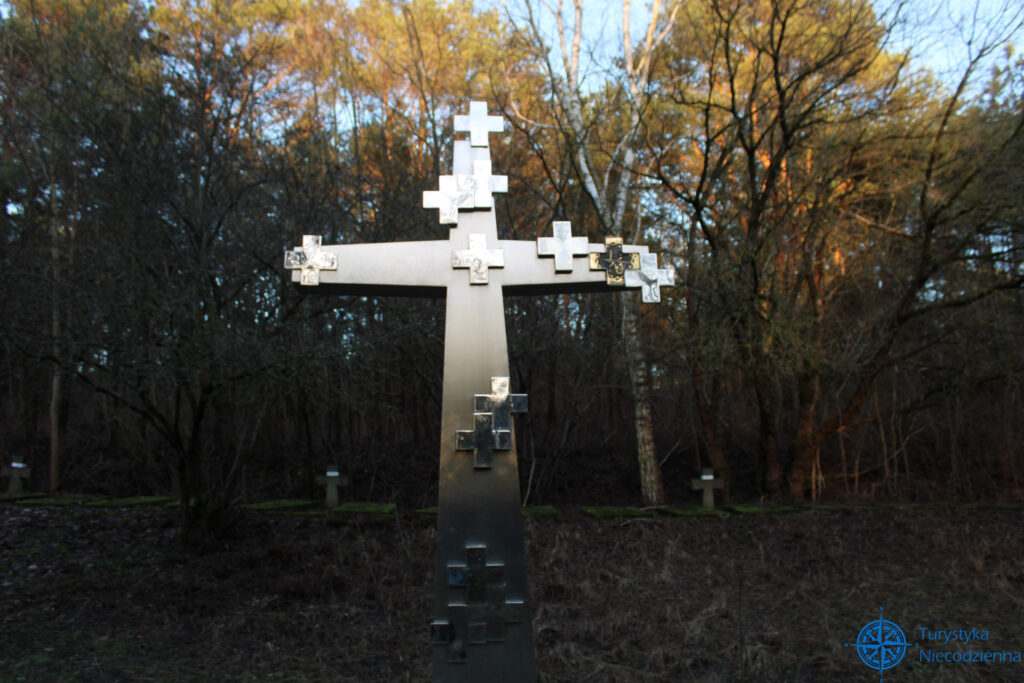Metalowy krzyż, na tle lasu przy zachodzącym słońcu