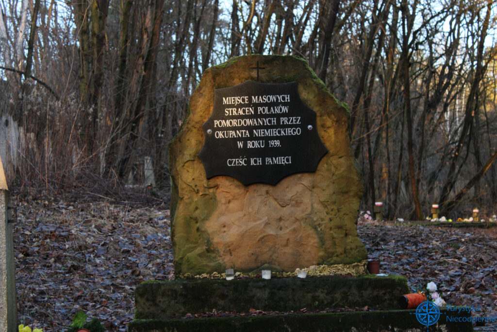 kamienny pomnik z tablicą głoszącą "miejsce masowych straceń polaków pomordowanych przez okupanta niemieckiego w roku 1939. Cześć ich pamięci"